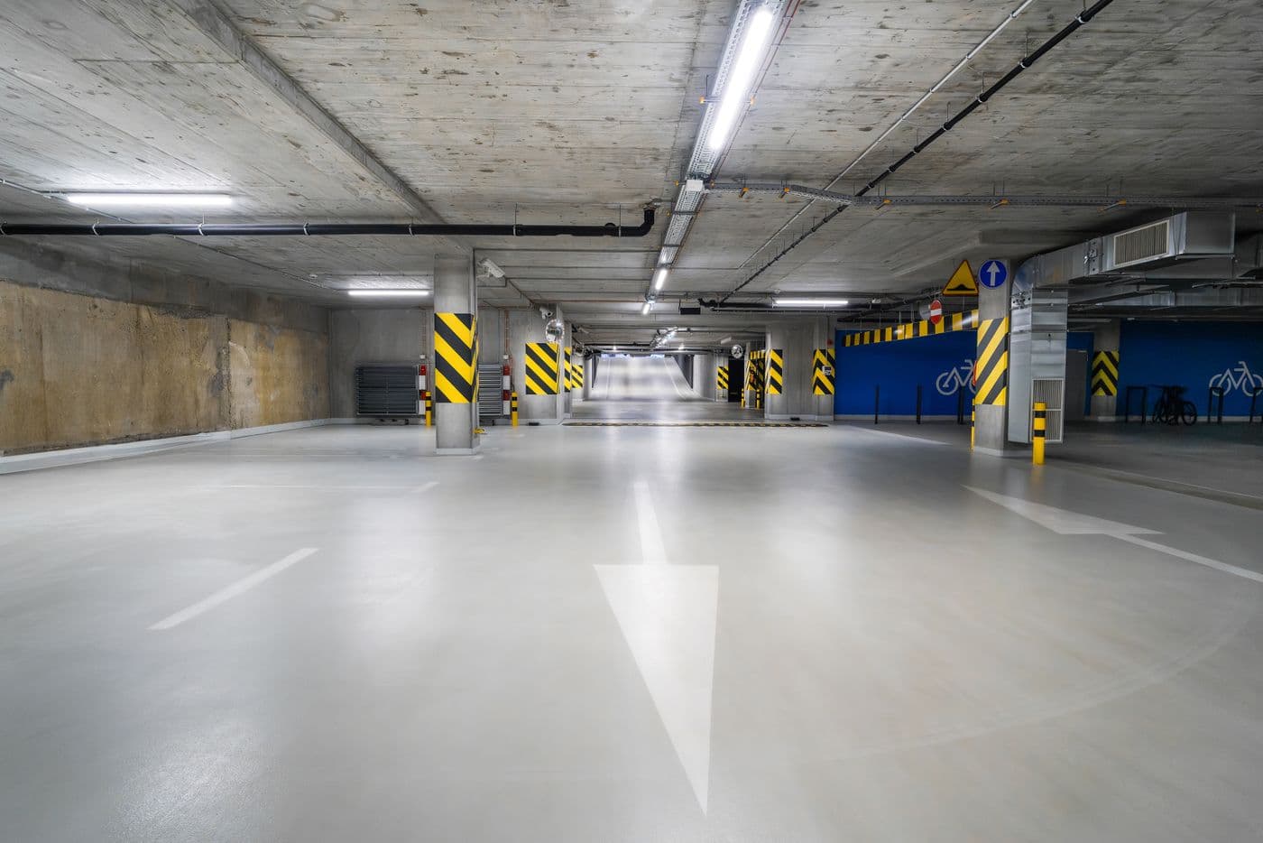 A clean, well-lit underground car park with marked bays and a bicycle rack